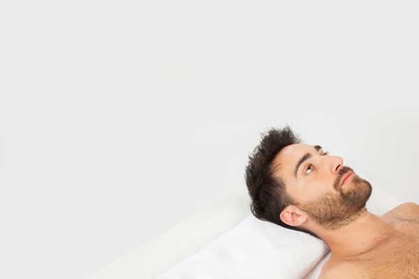 Dormir después del injerto de cabello - Hombre visiblemente agotado se acuesta boca arriba para recuperar energías