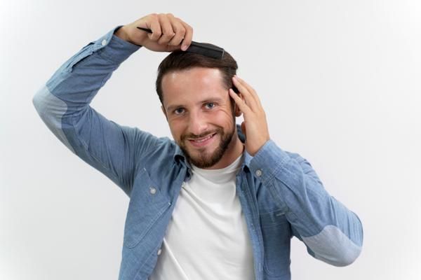 Edad para hacer injerto de cabello - hombre blanco con camiseta blanca y camisa vaquera de manga larga peinando su cabello hacia atrás
