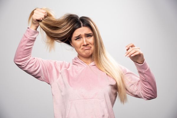 Se nos cae mucho el pelo - Mujer estresada y deprimida por la pérdida de cabello anormal que presenta, debido al consumo de pastillas anticonceptivas y los cambios hormonales que generan