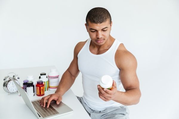 Se nos cae mucho el pelo - Hombre investigando en la computadora si los suplementos vitamínicos que consume generan problemas capilares, ya que está presentando una caída anormal de cabello tras su uso