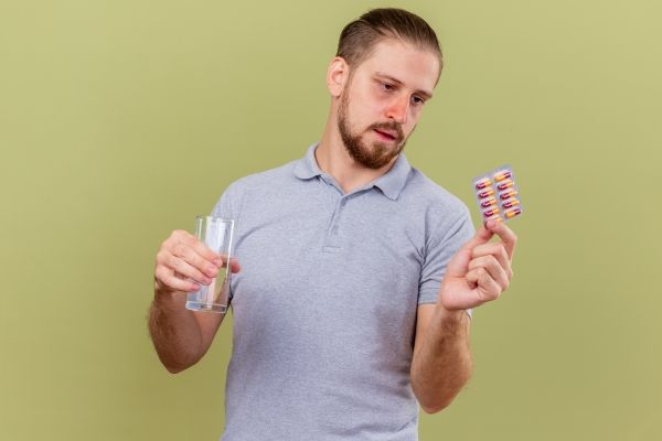 Hombre tomando pastillas para combatir la deficiencia de hierro, ya que la anemia puede causar la pérdida de cabello