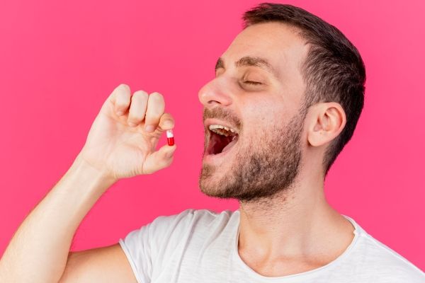 Hombre consumiendo un fármaco para controlar la presión arterial, el cual puede generar como efecto secundario la caída del cabello