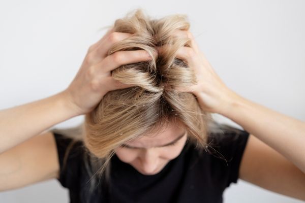 Mujer con fuerte picazón en el pelo, debido a una infección en el cuero cabelludo que inflama los folículos pilosos