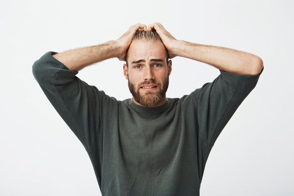 alopecia nerviosa - hombre llevándose las manos a la cabeza por las preocupaciones que le producen altos niveles de estrés