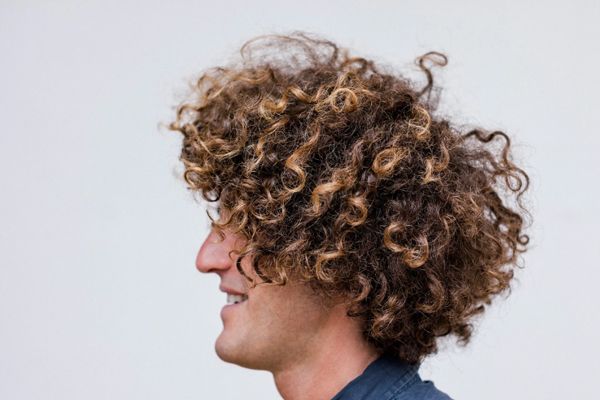 lavarse el cabello todos los días - hombre sonriente con el cabello rizado y seco