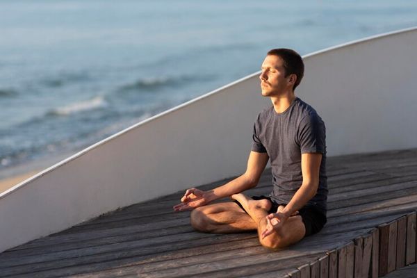 hombre haciendo meditación al lado del mar para reducir los niveles de estrés