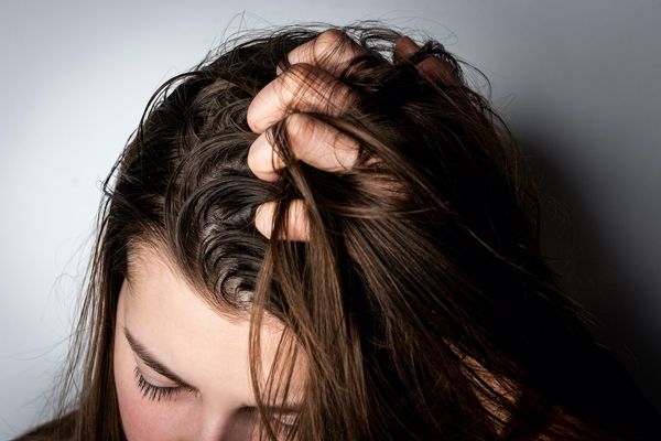 beneficios del vinagre para el cabello - mujer pasando las manos por su melena de cabello graso