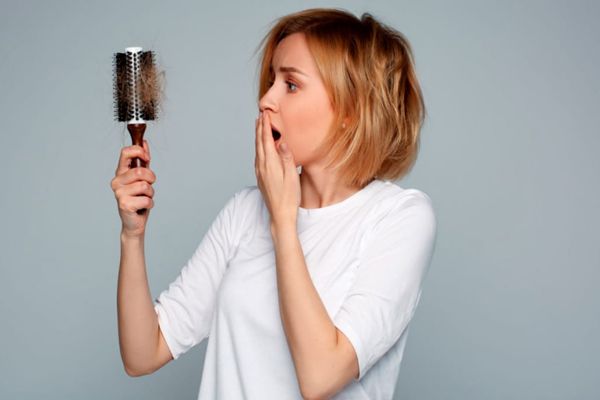 mujer preocupada por la cantidad de cabello que ha quedado en el cepillado tras el cepillado
