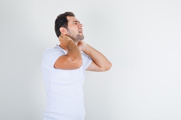 hombre llevándose las manos al cuello con cara de dolor