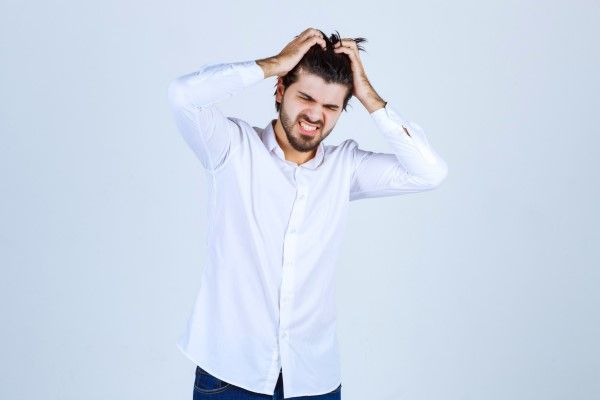 dormir con el pelo mojado - hombre agarrándose la cabeza con signos de dolor