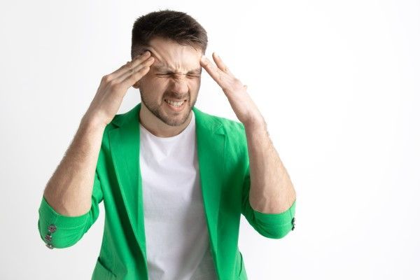 hombre llevándose las manos a las sienes con gesto de dolor