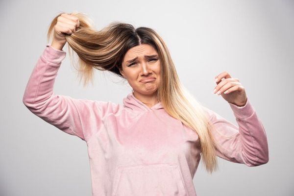 mujer con cara de dolor tirando de su pelo