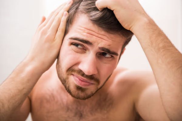 duele el cabello - hombre revisando su cabello con cara de sufrir ligeros dolores