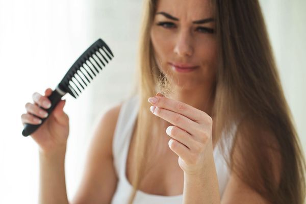 duele el cabello - mujer revisando un mecho de cabello que se ha quedado en el peine 