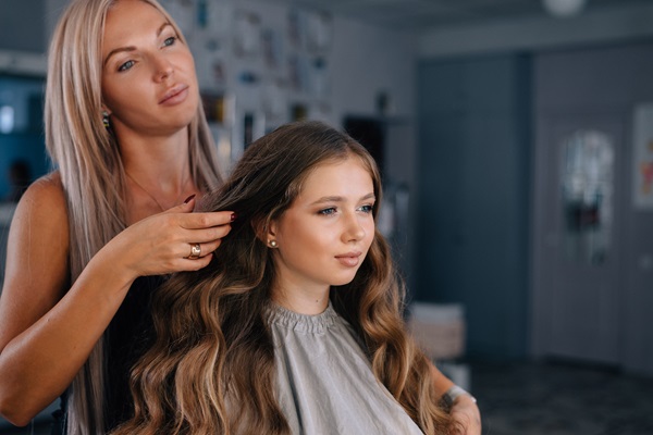 Estilista observando los resultados del peinado de su clienta, luego de arreglar su cabello con un nuevo estilo de ondas