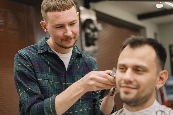 barbero cortando el cabello de un cliente masculino, para adaptar el look a la forma de su rostro y hacerlo lucir más atractivo