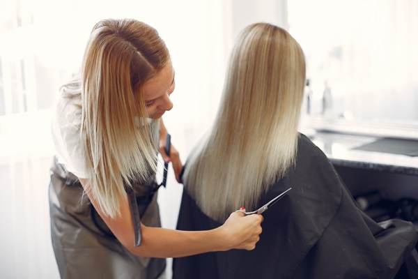 Estilista cortando las puntas abiertas de una clienta, para devolverle el look original a su cabello