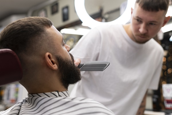 Barbero realizando un corte de cabello a un paciente masculino, adaptando el peinado de un famoso a sus características capilares