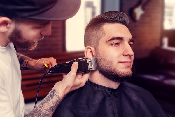 Cortes de pelo en el hombre según tu cara - Barbero realizando un corte de cabello a un hombre acorde a la forma de su rostro, para crear un look que lo haga lucir atractivo