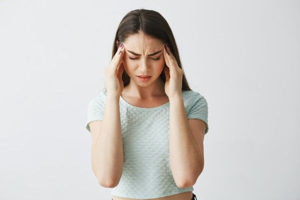 alopecia por tracción - mujer son la manos en las sienes y cara de dolor