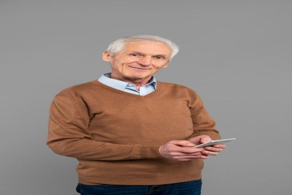 hombre mayor sonriente revisando su teléfono móvil