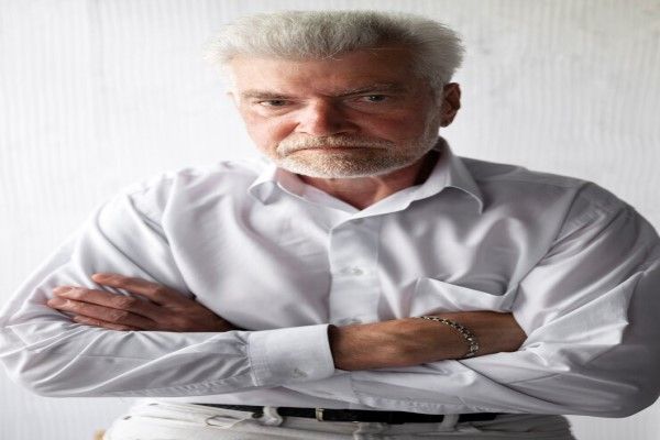 hombre mayor con cara de enfado y las manos cruzadas sobre el pecho