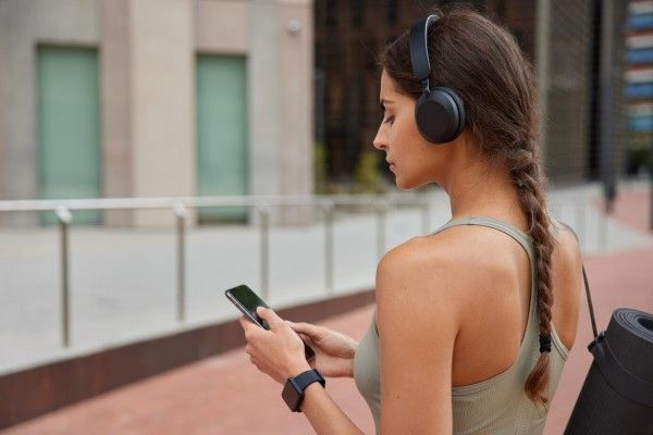 mujer con ropa deportiva y una trenza manipulando su teléfono móvil
