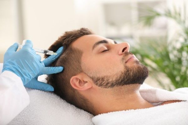 hombre en albornoz recibiendo un tratamiento para el cabello inyectable