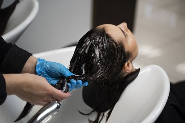 Estilista lavando el cabello de una mujer para aplicar el tratamiento de alisado