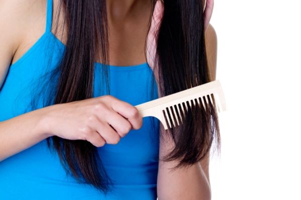 Mujer desenredando su cabello con un peine de dientes anchos para evitar dañarlo