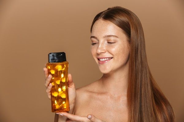 Biotina para el pelo - Mujer contenta con los resultados de su cabello al utilizar un champú que contiene vitamina B7