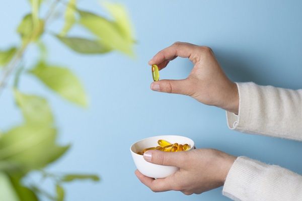 Persona sosteniendo una cápsula de vitamina B7 para fortalecer el cabello