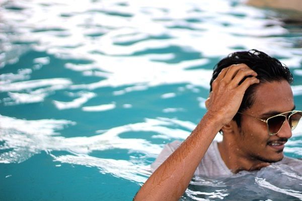 Revitalizar el pelo después del verano - Hombre tocando su cabello al bañarse en una piscina durante las vacaciones