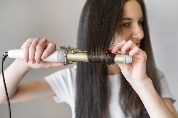 Keratina para el pelo - Mujer alisando su cabello con una plancha de pelo, luego del tratamiento con keratina