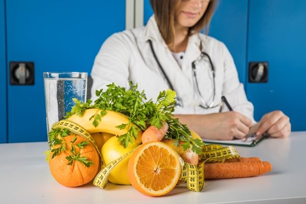 Doctora recetando diversos alimentos para mejorar la nutrición del pelo con frutas y hortalizas