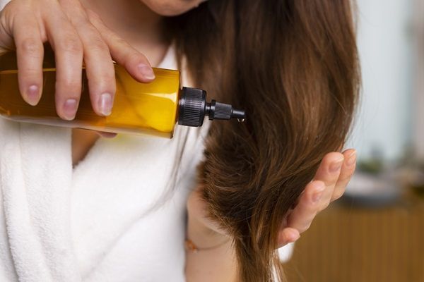 Keratina para el pelo - Mujer aplicando un tratamiento de keratina a su cabello para alisarlo y nutrirlo