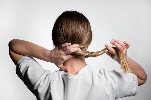 Keratina para el pelo - Mujer jugando con su cabello liso, haciendo una cola luego del tratamiento con keratina