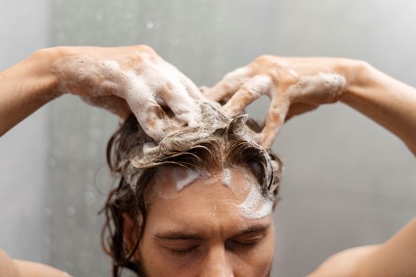 Champús para el crecimiento del pelo - Hombre frotando su cabello con el mejor champú para limpiarlo de manera correcta