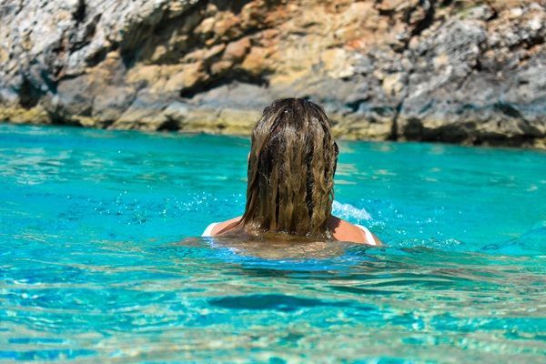 Revitalizar el pelo después del verano - Mujer bañándose en el mar durante las vacaciones