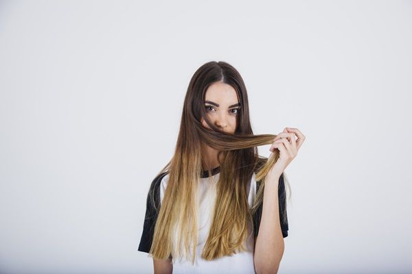 Mujer jugando con su cabello liso y nutrido unos meses después del tratamiento de alisado