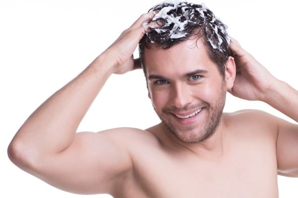 Estimular el crecimiento del cabello - Hombre feliz aplicando el mejor champú para hacer crecer el pelo
