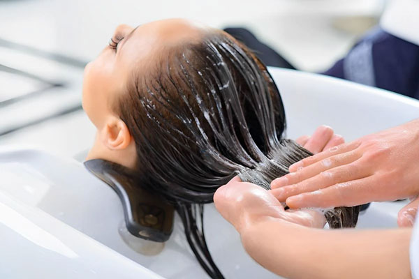 Botox capilar - Estilista realiza la aplicación de un producto capilar para recuperar el brillo natural del cabello