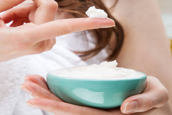 Botox capilar - Joven toma un poco de mascarilla intensiva para proceder a su distribución homogénea