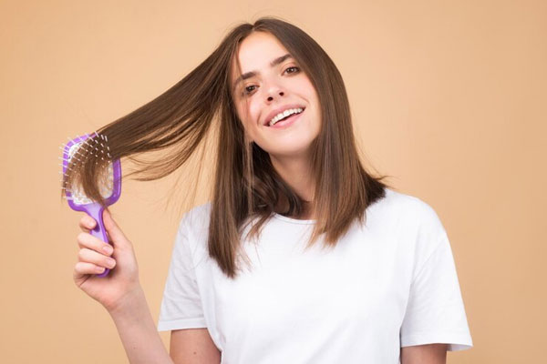 Pelo seco - Joven sonriente cepilla su cabello para mantenerlo sano y desenredado