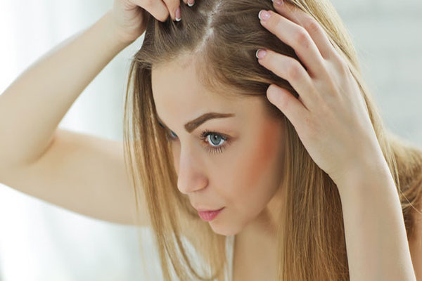 Botox capilar - Mujer rubia revisa su cuero cabelludo en busca de efectos secundarios adversos tras la aplicación de un tratamiento hidratante
