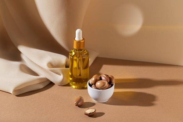 Aceite de argán para el pelo - Recipiente con aceite y semillas de argán que ayudan a nutrir el cabello
