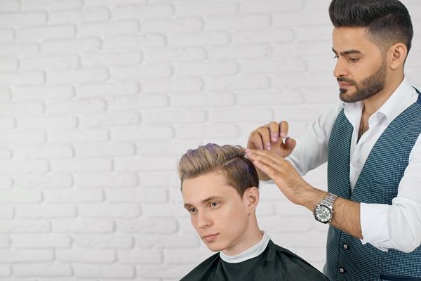 Peinados de hombre para bodas - Estilista realizando un corte de cabello despuntado, para brindar un look fresco al caballero el día de su boda