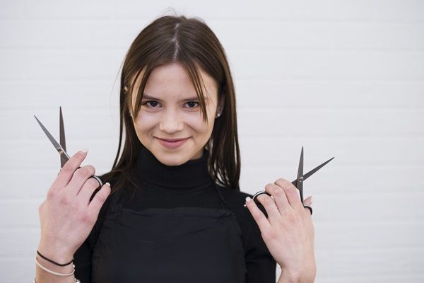 Cortes de pelo para cara redonda - Mujer con tijeras en las manos para realizar un corte de cabello que ayude a estilizar su cara redonda