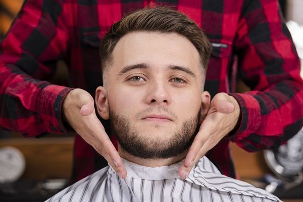 Estilista mostrando los resultados del corte de cabello a un hombre con rostro redondo