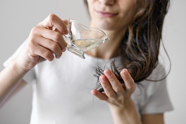 Aceite de oliva - Mujer colocando unas gotas de aceite de oliva en su cabello, para hidratarlo y reparar las puntas abiertas